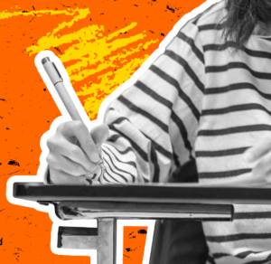 A person at a desk writes in a notebook, reporting or documenting.